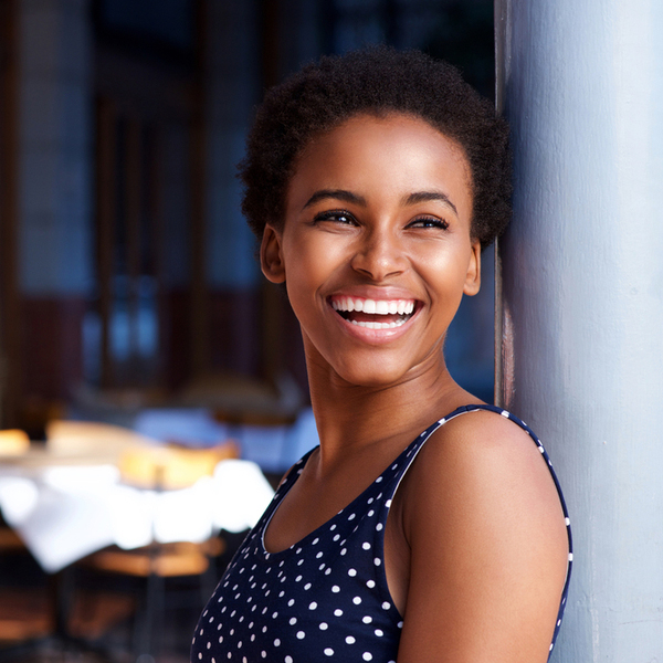 Full Mouth Reconstruction Young Woman Laughing While Leaning Against the Wall